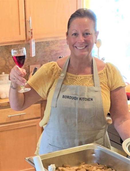 imagen de mujer en la cocina disfrutando de una copa de vino mientras cocina