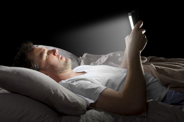 Man in bed looking at phone