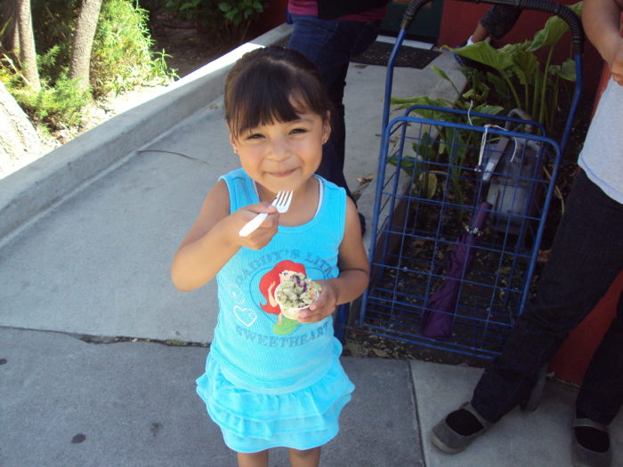 small girl eating food from a bowl