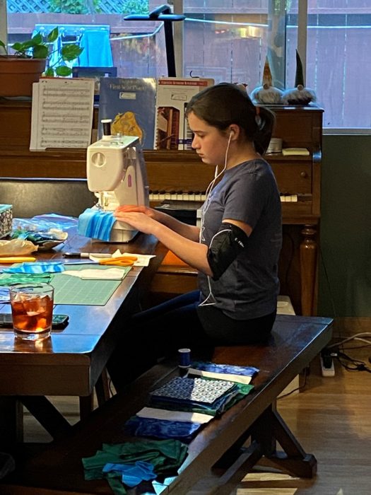 girl sewing at a table listening to music