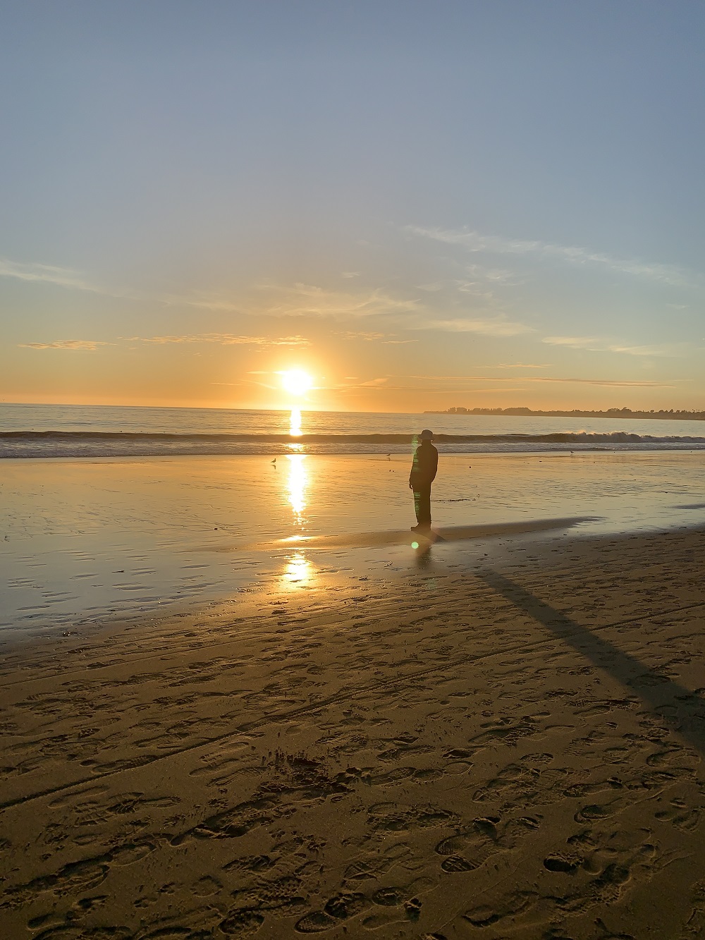 persona viendo la puesta de sol en la playa