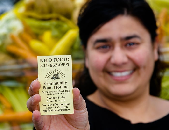 imagen de una mujer sosteniendo una tarjeta de visita con el Banco de Alimentos de la Segunda Cosecha
