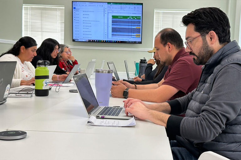 people working on laptops around table in meeting room
