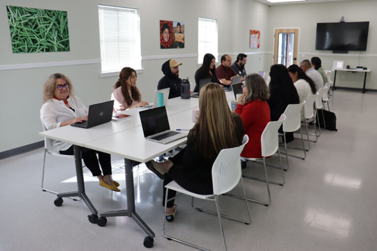 people working on laptops around table in meeting room