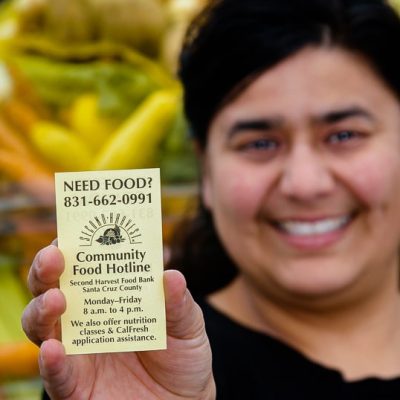 imagen de una mujer sosteniendo una tarjeta de visita con el Banco de Alimentos de la Segunda Cosecha